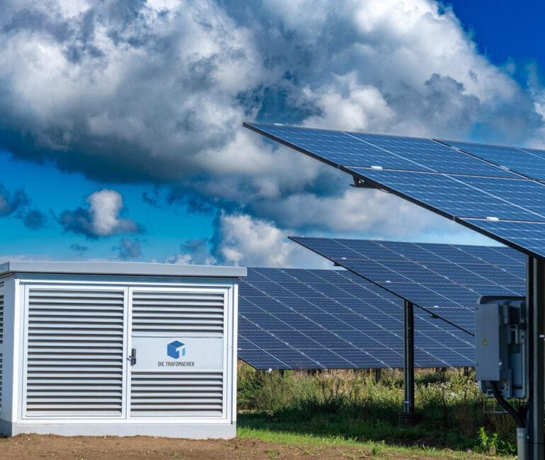 Wiese mit Solarpark und Trafostation bei leicht bewölktem Himmel