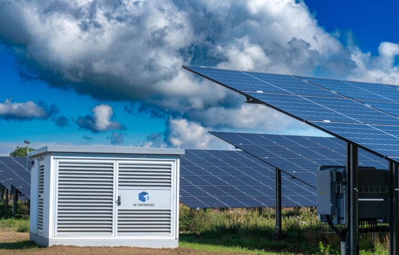 Wiese mit Solarpark und Trafostation bei leicht bewölktem Himmel